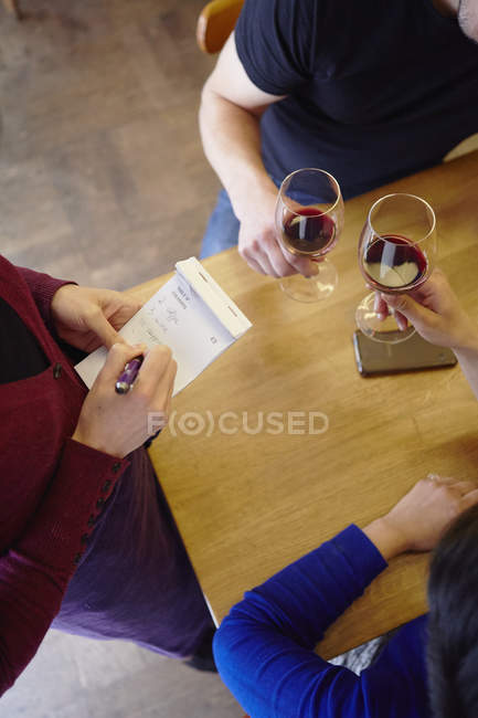 Cropped shot of waitress taking order in restaurant from couple — Stock Photo