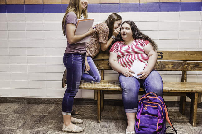 Teenage high school girls whispering in corridor — Stock Photo