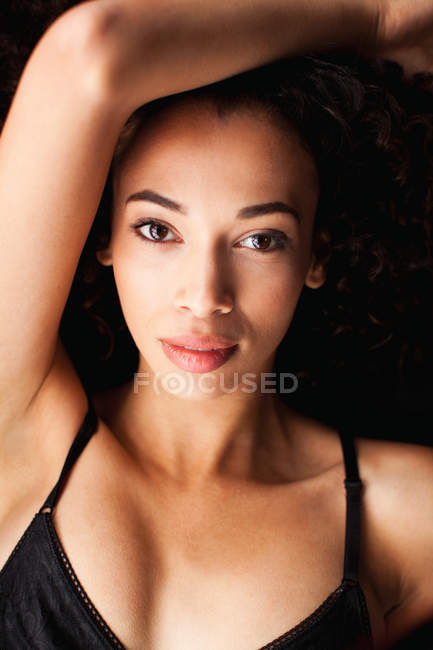 Young woman in against black background, portrait — Stock Photo