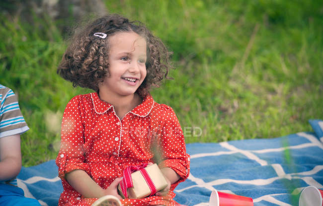 Chica sosteniendo regalo en el picnic de cumpleaños - foto de stock