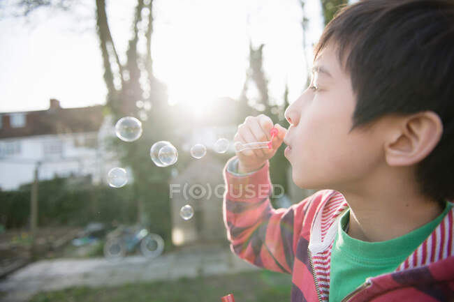 Garçon soufflant des bulles avec baguette, gros plan — Photo de stock