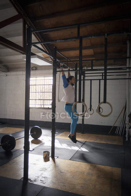 Crossfitter faire pull ups dans la salle de gym — Photo de stock