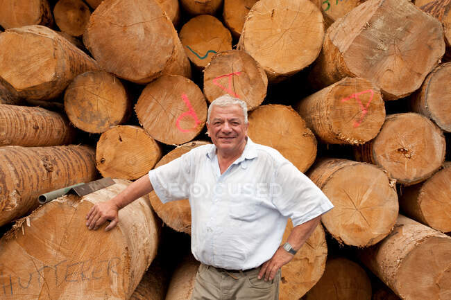 Uomo per mucchio di tronchi — Foto stock