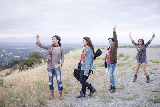 Four adult sisters posing for smartphone selfie on rural hill — Stock Photo