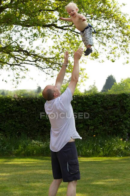 Отец подбрасывает маленького сына в воздух — стоковое фото