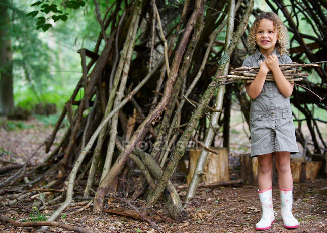 Chica joven con un montón de ramitas en el bosque - foto de stock