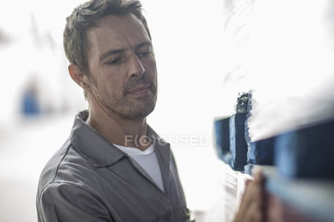 Cape Town, South Africa, male worker in overalls wiping off from crate in packaging factory — Stock Photo