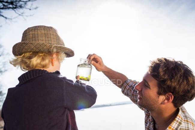 Father and son collecting jar of water — Stock Photo