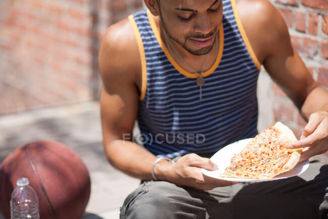 Basketball joueur avec une tranche de pizza — Photo de stock