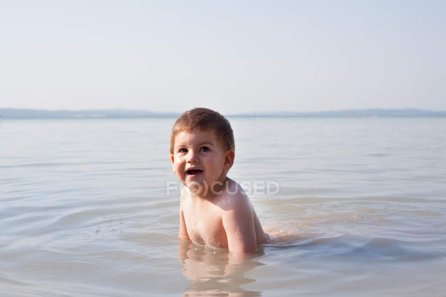Menino brincando na água ao ar livre — Fotografia de Stock