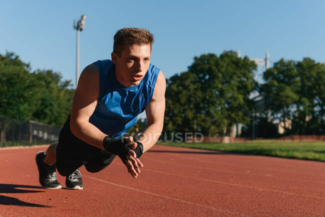 Jeune homme faisant de l'exercice sur piste sportive — Photo de stock