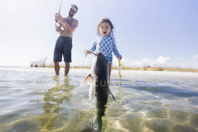 Daughter watching father catch fish in sea, Fort Walton Beach, Florida, USA — Stock Photo