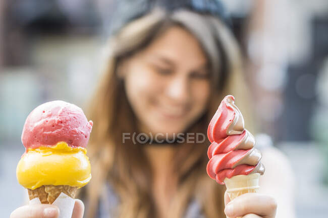 Young woman holding ice cream cones on street — Stock Photo