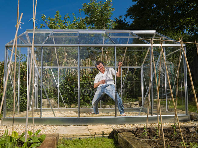 Man playing air guitar in greenhouse — Stock Photo