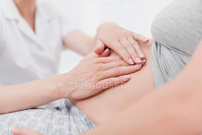 Médico examinando el vientre de la mujer embarazada - foto de stock