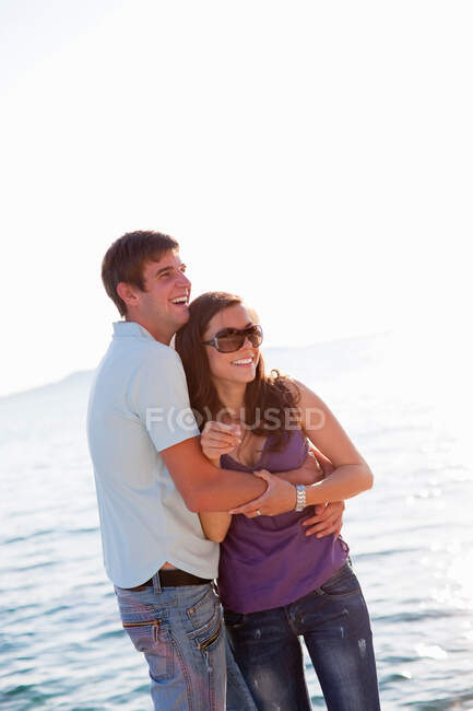 Couple hugging by water — Stock Photo