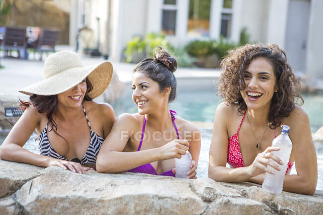 Tres hermanas adultas con tops de bikini charlando en el jardín - foto de stock