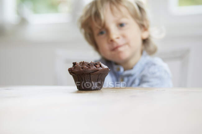 Молодий хлопець дивиться на шоколадний кекс — стокове фото
