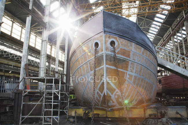 Casco de barco iluminado por el sol en taller de astilleros - foto de stock