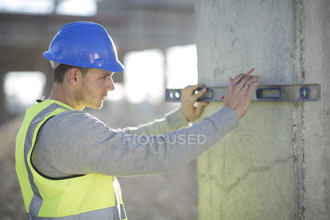 Arpenteur utilisant le niveau d'esprit sur le pilier du chantier — Photo de stock