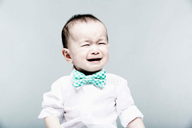 Portrait of baby boy wearing shirt and bow tie, crying — Stock Photo