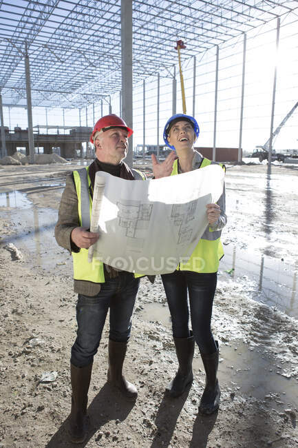 Architect and builder looking up on construction site — Stock Photo