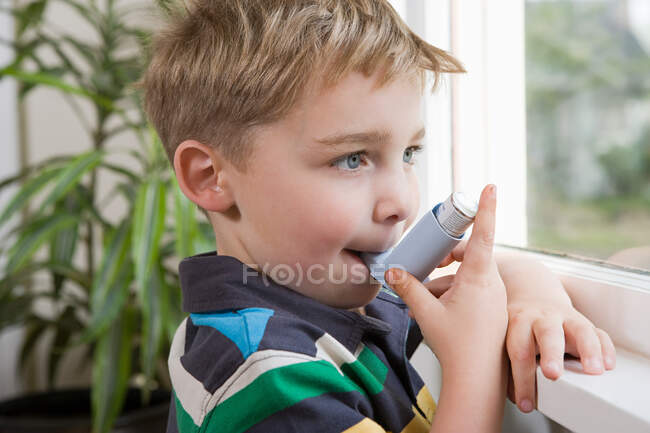 Niño tomando inhalador de asma - foto de stock