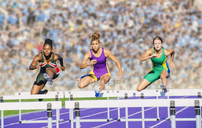 Runners jumping over hurdle on track — Stock Photo