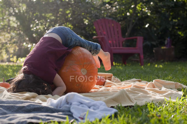Girl lying on pumpkin in the garden — Stock Photo