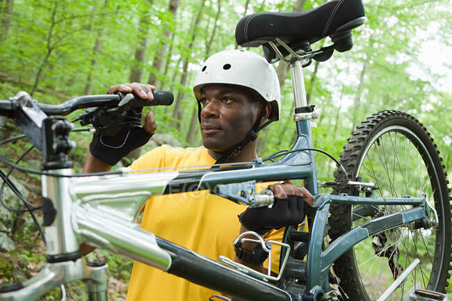 Male cyclist carrying bike in forest — Stock Photo