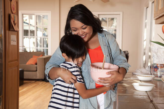 Boy hugging mother  in kitchen — Stock Photo