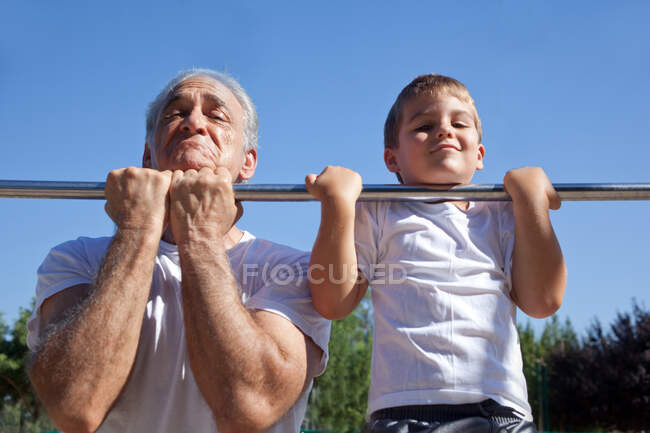 Man and grandson doing chin-ups — Stock Photo
