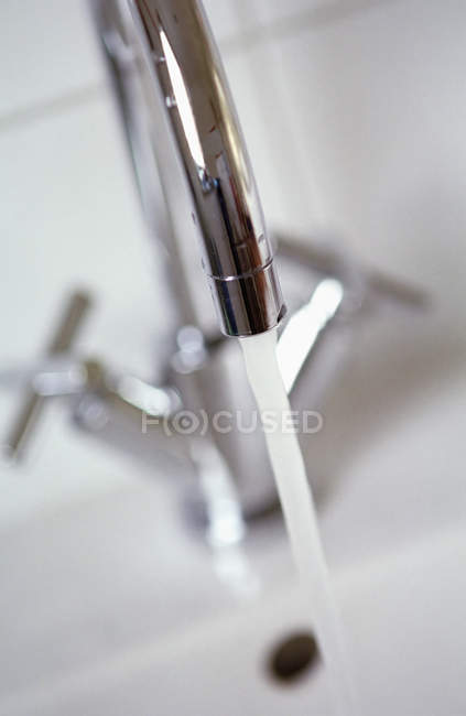 Close up de água derramando de torneira de metal — Fotografia de Stock