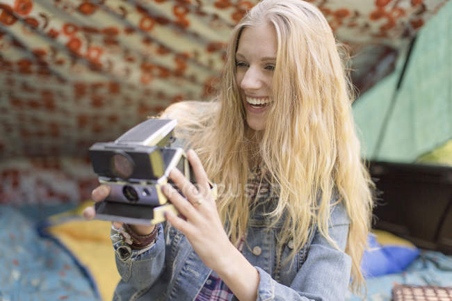 Jovem fotografa com câmera instantânea enquanto acampa — Fotografia de Stock