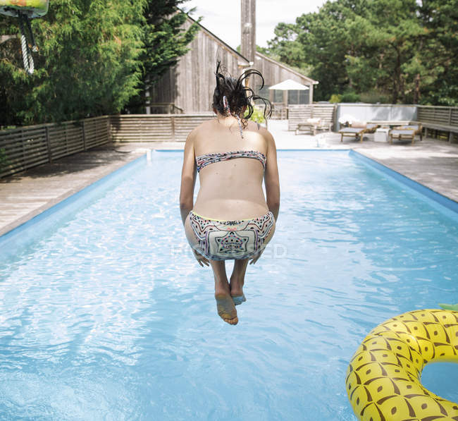Woman jumping into swimming pool, Amagansett, Nueva York, Estados Unidos - foto de stock