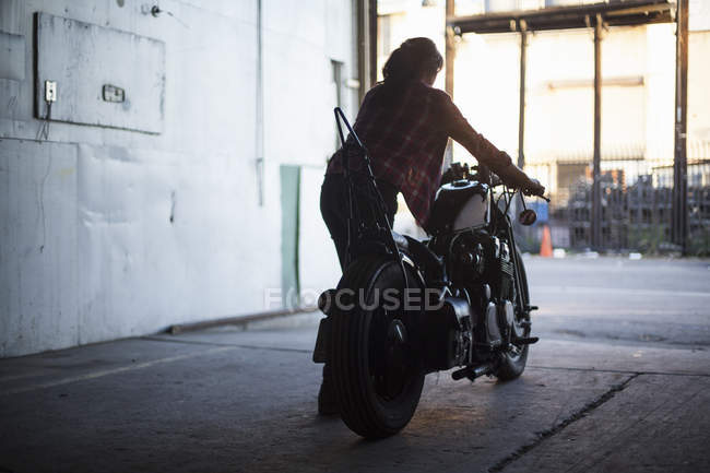 Mécanique féminine travaillant sur moto en atelier — Photo de stock