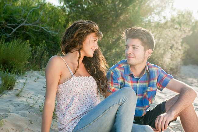 Молода пара сидить на піску — стокове фото
