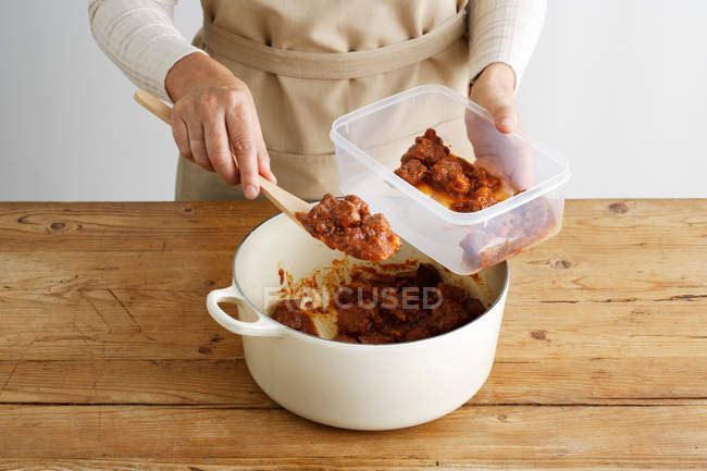 Abgeschnittenes Bild einer Frau, die in der Küche Fleisch in Plastikbehälter löffelt — Stockfoto