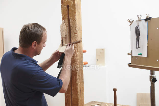 Worker chiseling figure from wood — Stock Photo