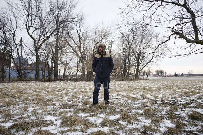 Porträt eines reifen Mannes in verschneiter ländlicher Umgebung mit Trappermütze — Stockfoto