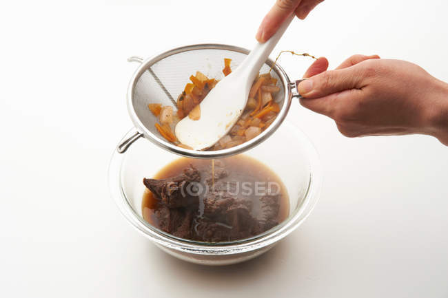 Femelle main filtrage bouillon de légumes à partir du tamis — Photo de stock