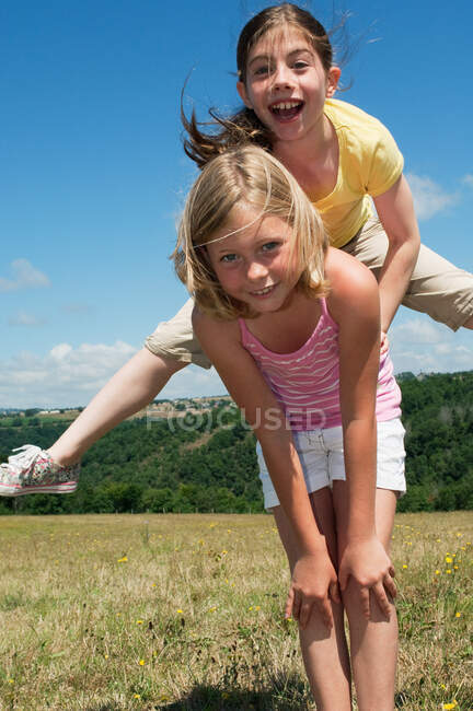Two girls playing leapfrog in field — Stock Photo