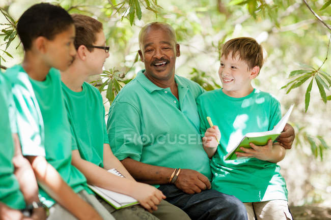 Students writing outdoors with teacher — Stock Photo
