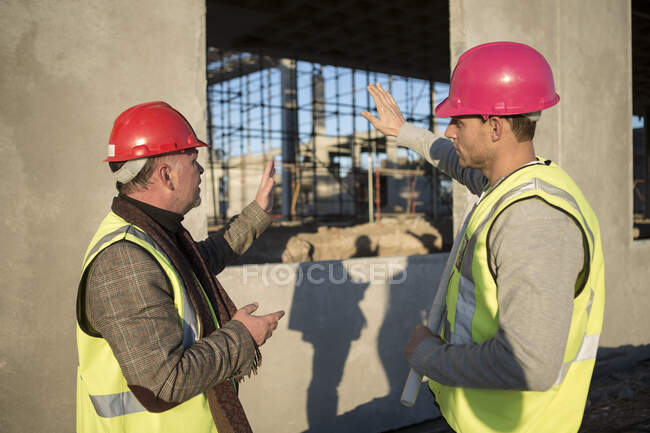 Arquitecto y constructor discutiendo marco de ventana en el sitio de construcción - foto de stock