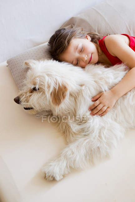 Mädchen entspannt sich mit Hund im Bett — Stockfoto