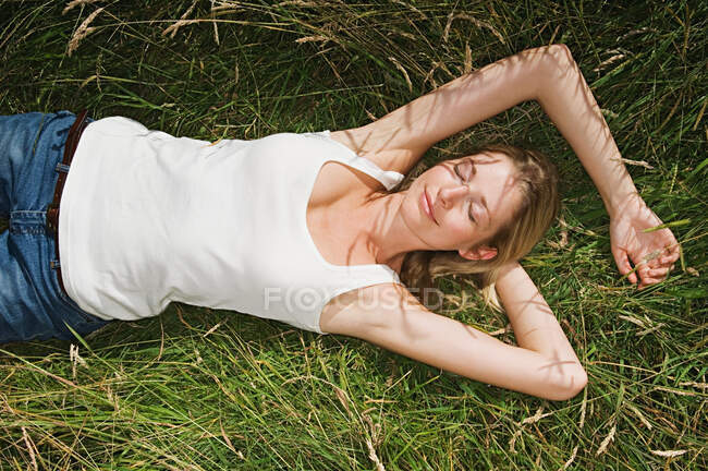 Mujer durmiendo en un campo - foto de stock