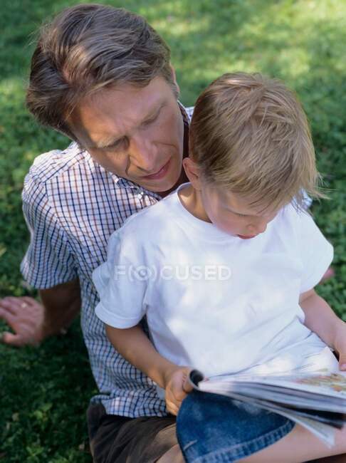 Батько і син читають на відкритому повітрі — стокове фото