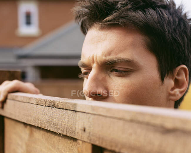 Hombre mirando por encima de la cerca del jardín - foto de stock