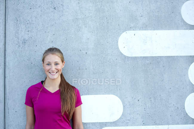 Lächelnde Frau lehnt an Wand — Stockfoto