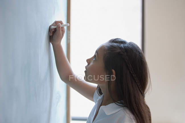 Girl writing a sum on a blackboard — Stock Photo